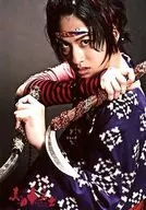 Atsushi 白又 (Kamanosuke Yuri) / Upper body, costume purple, red, body facing left, both hands weapon, background black, Character Tomoshot / "Sanada Juyushi ~ If you're not cool, you just die ~" Official photo