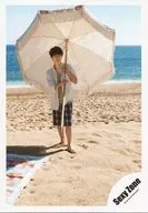 SeXyzone / Marius Yo / Whole body ・ Costume with white, green and blue check ・ Holding parasol with both hands ・ Body front ・ Background sea ・ Sandy beach / 17 Early Winter Marius Yo Spanish Offshot / Official Official photo