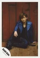 KinKi Kids / Koichi Domoto / Whole body, sitting, costume blue, stole black and white dot pattern, right knee standing, left hand floor, eye view right, background red brown, board / official Official photo