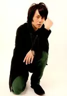 根本正勝/全身・しゃがみ・衣装黒緑・右手上げ・左膝立て・背景白/生写真