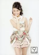 9 nine / Kanae Yoshii / Above Knee / Green Costume / Pink. White / Flower Pattern / Right Hand Cheek / Left Hand Raised / Official Official photo