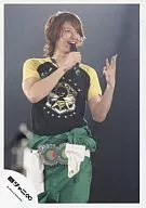 Kanjani Eight / Tadayoshi Okura / Live Photo / Above Knee / Black / Yellow Shirt / Green Pants / 3 the left fingers Stand / Microphone on Right Hand / Eye View / Smile / Background Black / Official Official photo