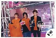 V6 / Takeshi Morita, Ken Miyake, Junichi Okada / Horizontal, Above-the-knee, Shirt orange, Background pink, Concert goods in both hands