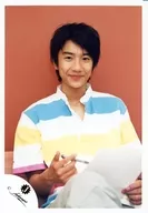 Johnnys / Jun Hasegawa / Upper body, sitting, costume white, light blue, yellow, pink, right hand ball point pen, background brown / Official Official photo